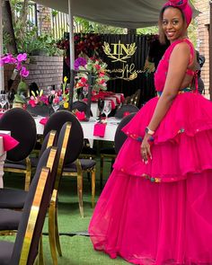 a woman in a pink dress standing next to a table