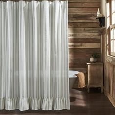 a white shower curtain in a bathroom with wood walls and flooring on the side