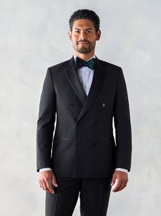 a man in a tuxedo is posing for a picture with his hands in his pockets