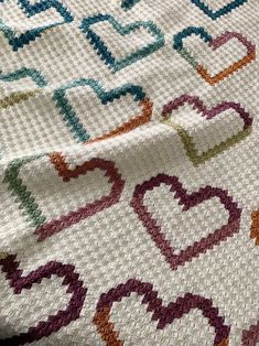 a multicolored rug is laying on top of a tablecloth that has hearts drawn on it