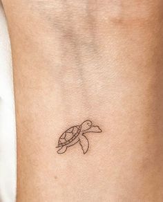 a small turtle tattoo on the back of a woman's leg, with an arrow in