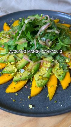 a black plate topped with yellow peppers and green salad dressing on top of a wooden table