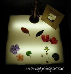 a lit up table with flowers on it and a mirror in the corner behind it