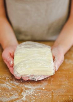 a person holding dough in their hands on a wooden table