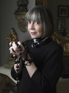 a woman in a black shirt is holding some beads