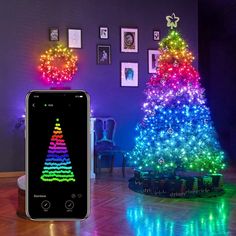 a cell phone sitting on top of a wooden floor next to a lit christmas tree