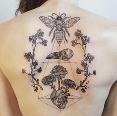 a woman's back with tattoos on her body and flowers in the shape of a triangle