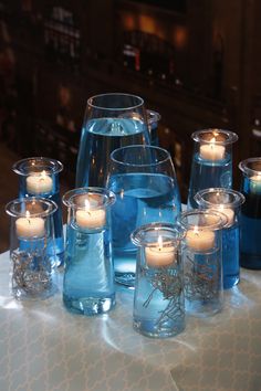 blue glass vases with lit candles on a table