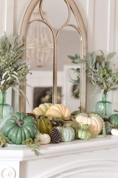 a fireplace mantel decorated with pumpkins and greenery in front of a mirror