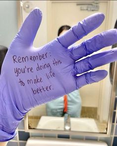 a purple glove with writing on it in front of a bathroom mirror and people sitting at the sink