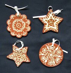 four wooden ornaments are hanging from strings on a black background, with white swirls and snowflakes