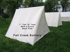 three tents with white tarps sitting in the grass