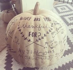 a white pumpkin with writing on it sitting on a rug in front of a door