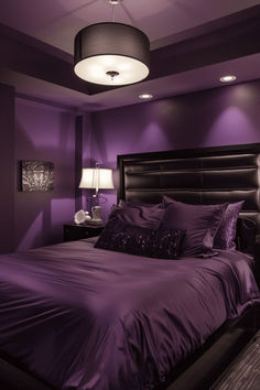 a bed with purple sheets and pillows in a dark colored room, lit by two lamps