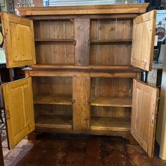 an old wooden cabinet with two doors and shelves in the center, open to reveal other items