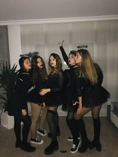 four girls dressed up in costumes posing for the camera with one girl pointing at something