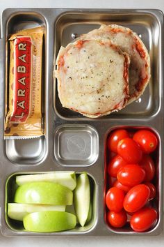 an open lunch box with some food in it, including tomatoes, apples, and cheese