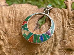 This beautiful Inca Calendar pendant is made by hand by the beautiful Quechua people of the Peruvian Andes.  It is made by  Silver, and Gemstones from the region (Mother of Pearl, Lapiz Lazuli, Crystacola, Spondyllus, Avalon) Weight : 6.4 gr Diameter:  3.1 cm Height with the hook: 4.5 cm It is handmade in 950 silver with inlaid stone and shell by a local family of jewelry artisans. Green Bohemian Jewelry With Inlay, Bohemian Pendant Necklaces With Inlay, Bohemian Pendant Necklace With Inlay, Bohemian Green Jewelry With Inlay, Bohemian Green Inlay Jewelry, Bohemian Round Necklace With Inlay, Hummingbird Pendant, Le Crochet, Stone Inlay