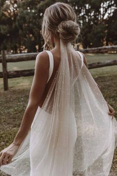 the back of a woman wearing a white wedding dress with sheer, beaded detailing