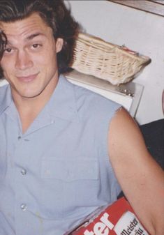 a young man sitting in a chair holding a can of soda and looking at the camera