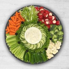 an arrangement of vegetables arranged in a circle on a platter with dip and radishes