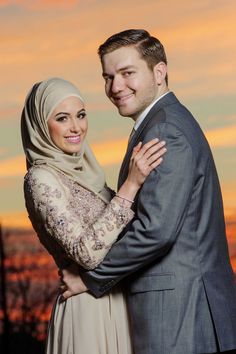 a man and woman standing next to each other in front of a sky with clouds