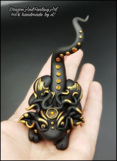 a hand holding a black and gold ring with an octopus on it's face