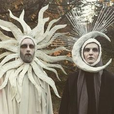 two men with sun and moon masks on their heads are standing next to each other