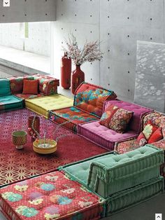 colorful couches are arranged in the middle of a room with vases and flowers