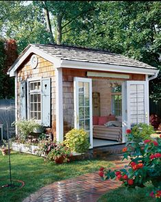 a small wooden shed sitting on top of a lush green field next to a garden