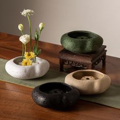 three vases with flowers in them sitting on a wooden table next to a green mat