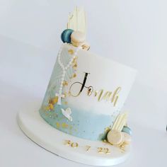 a blue and white cake with the word joy on it's side, surrounded by seashells