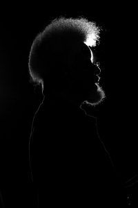 black and white photograph of a man in the dark with his head turned to the side