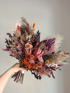 a person holding a bouquet of flowers in their hand, with the stems and leaves still attached to it