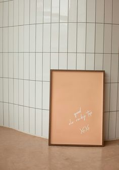 a white tile wall with a pink frame on the floor in front of it that says, i am sorry to you