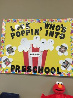 a bulletin board with popcorn on it next to a stuffed animal