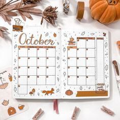 an open planner book sitting on top of a table next to fall leaves and pumpkins