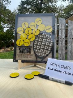 a tennis racket and some yellow ping pong discs on a table with a sign