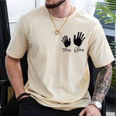 a man sitting in a chair wearing a t - shirt with two hand prints on it