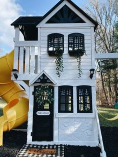 a white house with black shutters and a yellow slide