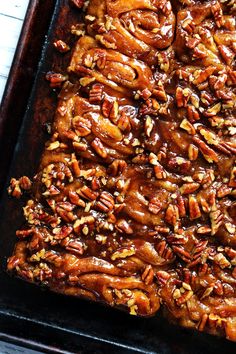 a pan filled with pecans and caramel on top of a white tablecloth