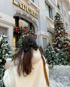 a woman walking down the street in front of a building with christmas decorations on it