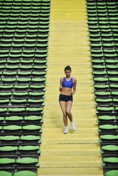 a woman is standing in the middle of a row of empty stadium bleachers