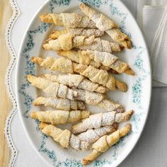 a white plate topped with pastries covered in powdered sugar on top of a wooden table