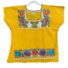 Gorgeous Floral Embroidered Blouse, Flattering Cut, Short Sleeves. Cotton Fabric And Silk Thread Embroidery. Any Accessories Shown Are Sold Separately. Every Sale It's Helping To Support More Than 20 Artisan Families From Oaxaca, Chiapas, And Puebla, Thank You! Please Note That The Patterns And Colors Of The Embroidery May Vary. If You Have A Specific Request, Contact Us Before Placing The Order. Yellow Embroidered Short Sleeve Top For Spring, Traditional Yellow Blouse For Spring, Embroidered Yellow Summer Blouse, Yellow Embroidered Summer Blouse, Embroidered Yellow Blouse For Summer, Yellow Bohemian Tops With Floral Embroidery, Bohemian Yellow Tops With Floral Embroidery, Yellow Short Sleeve Embroidered Casual Top, Yellow Casual Short Sleeve Embroidered Top