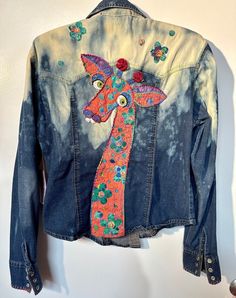 a denim jacket with a tie - dyed design on the back and colorful flowers painted on it