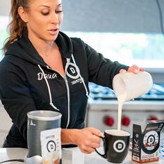 a woman pouring coffee into two mugs