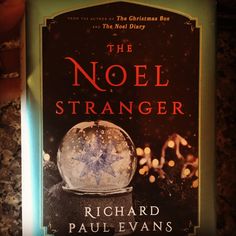 a book cover for the novel the noel stranger by richard paul evans on a table