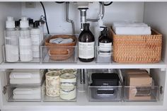 an organized bathroom shelf with bottles, soaps and toiletries in the bottom drawer