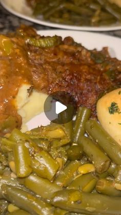 a plate with green beans, mashed potatoes and gravy next to other food